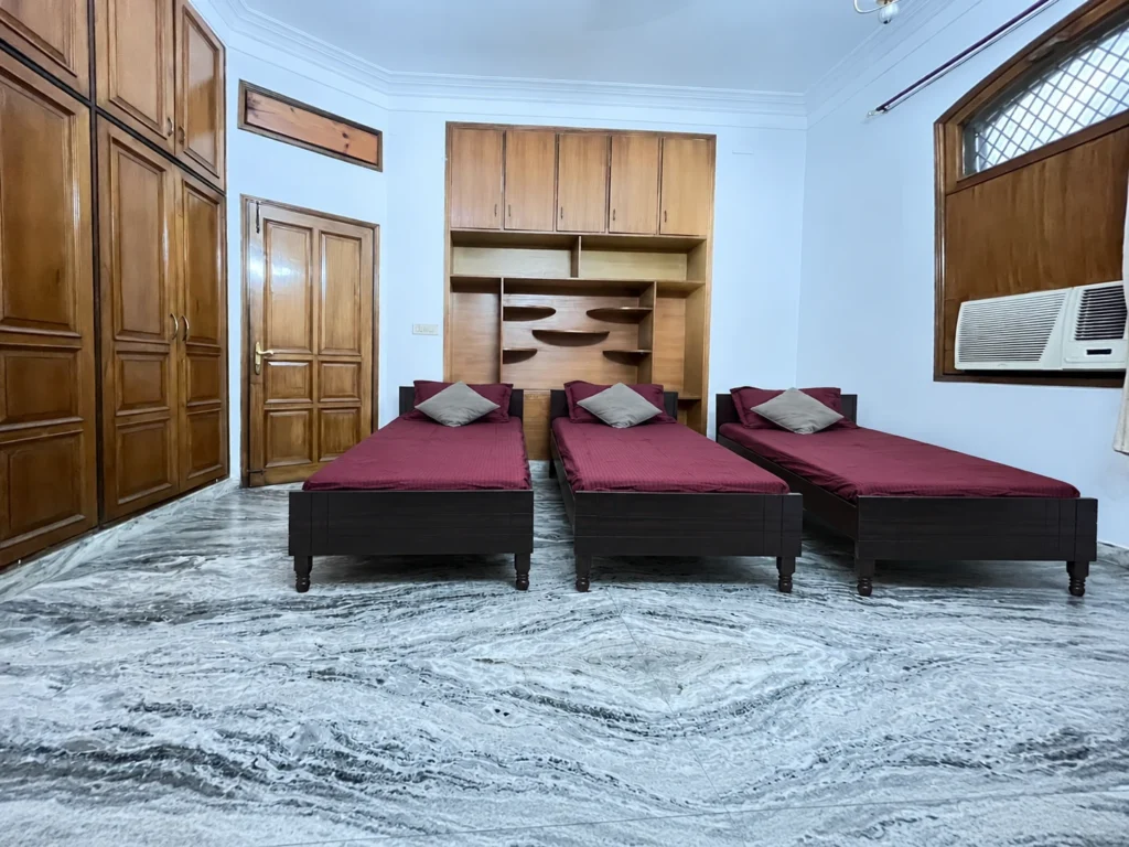 Triple-sharing room with brown wooden beds and wardrobes at GableStay