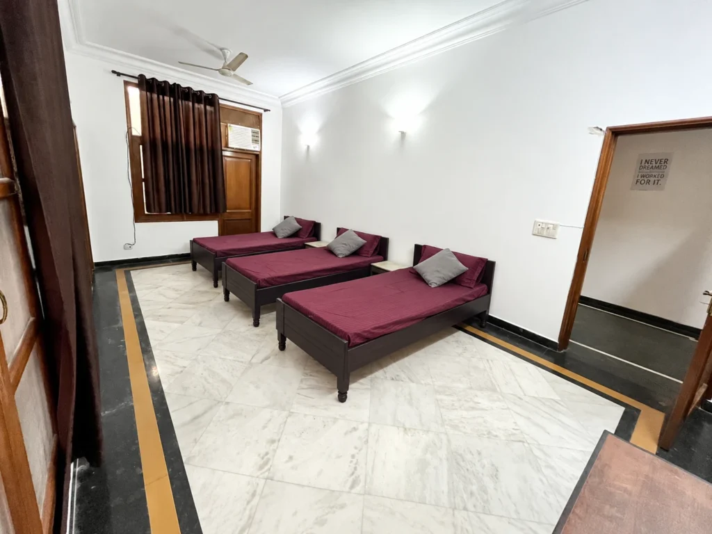 Girls’ triple-sharing PG room with three furnished beds at GableStay Sector 33, Noida